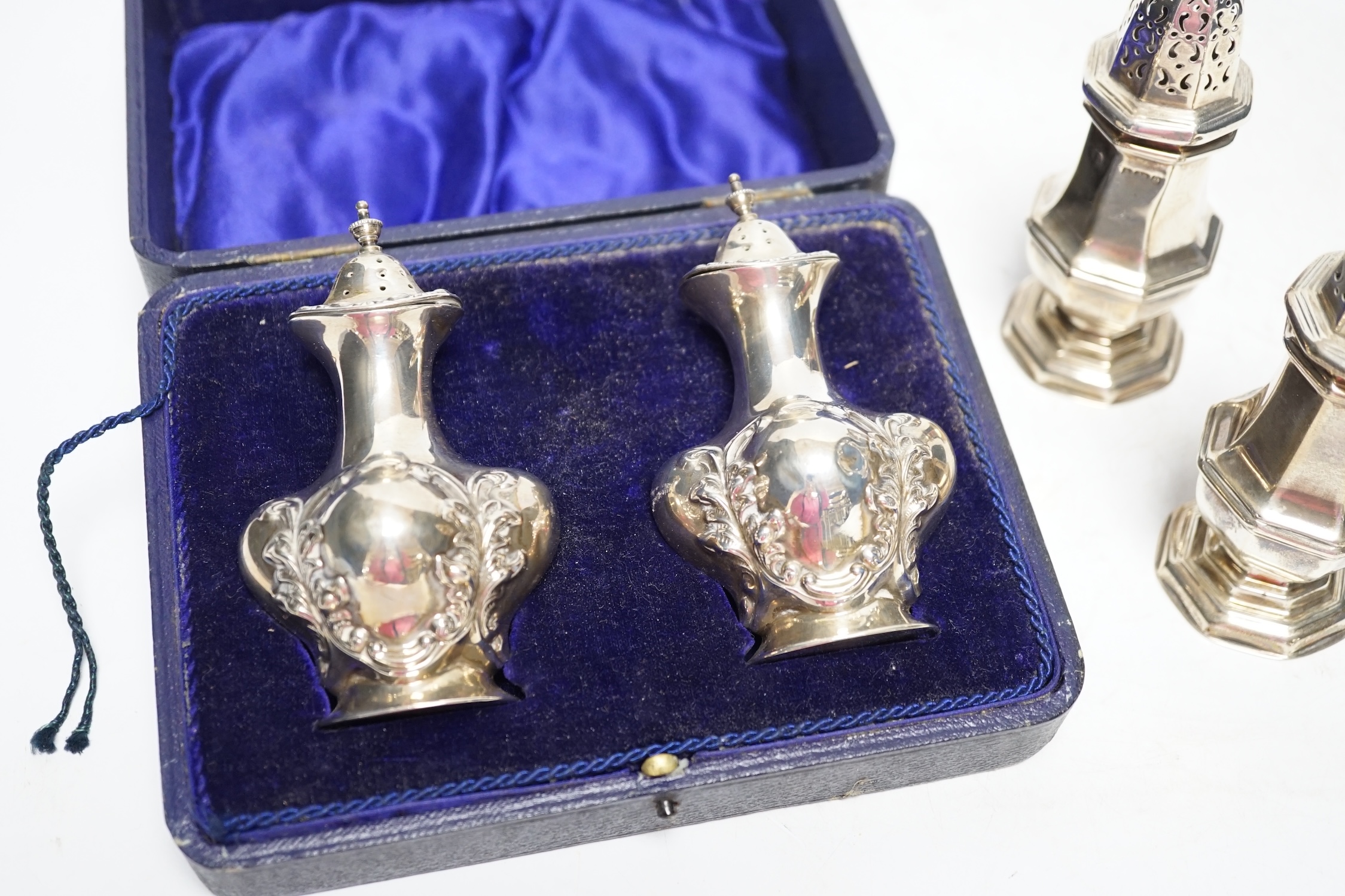 A cased pair of George V silver pepperettes, by Joseph Gloster Ltd, Birmingham, 1912, 98mm and a pair of Edwardian silver octagonal pepperettes, 6.3oz. Fair condition.